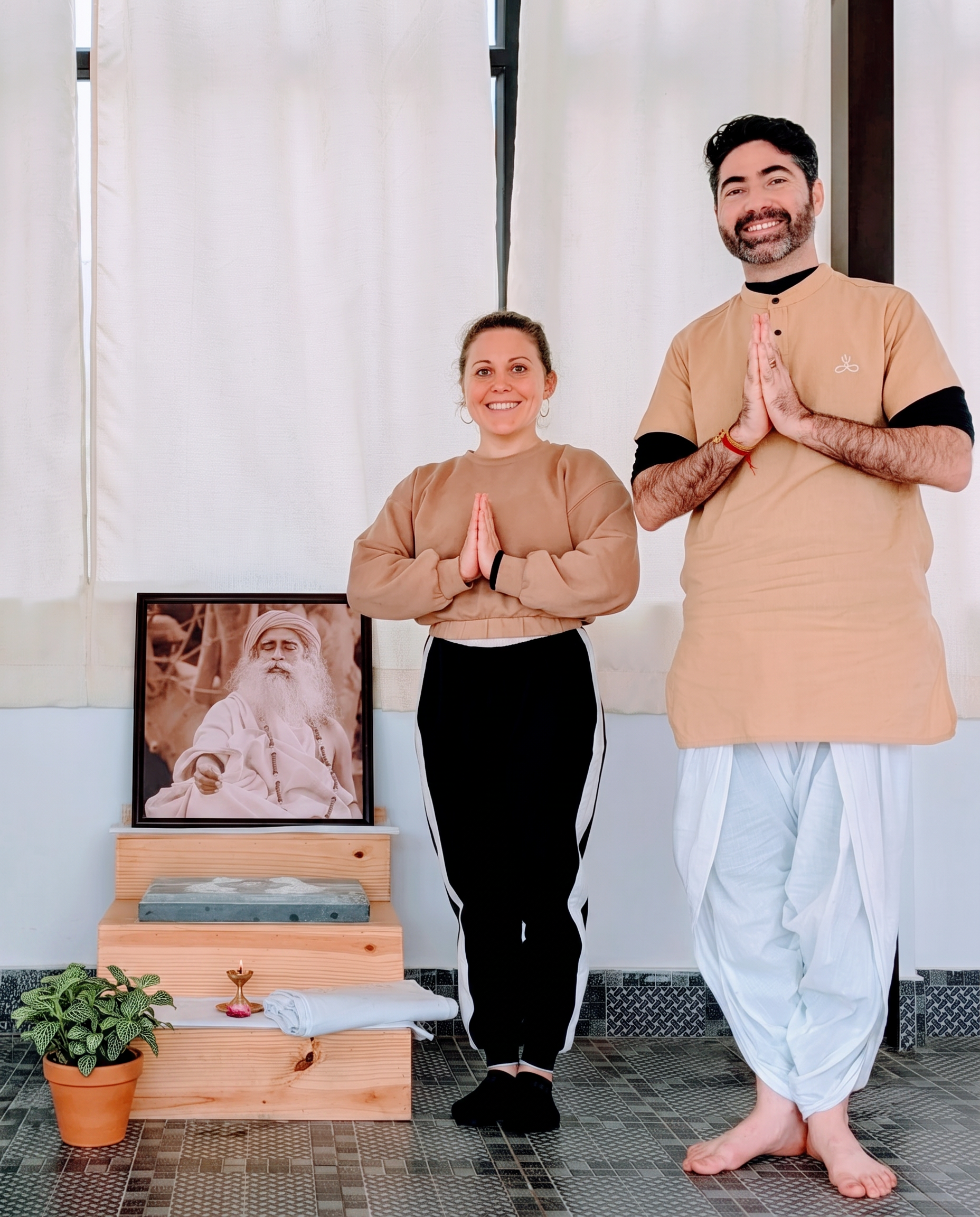Students standing in Namaskar beside a portrait of Sadhguru